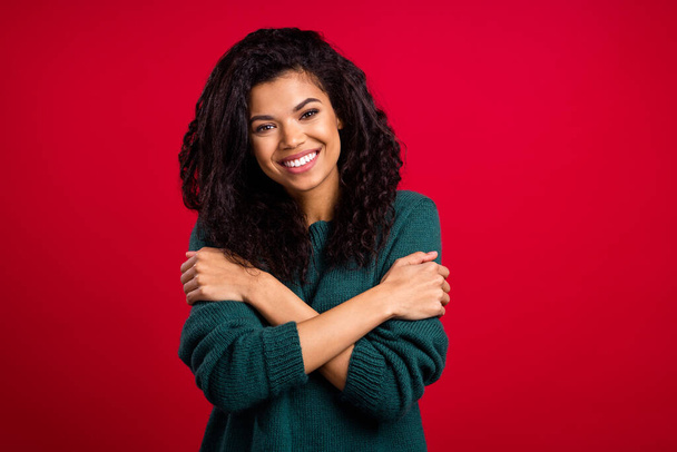 Photo of attractive nice dark skin young woman smile hug herself comfort isolated on red color background - Φωτογραφία, εικόνα