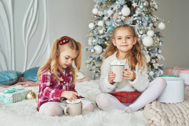 Two baby girls sisters on background christmas tree. Happy family. Friendship concept. - Φωτογραφία, εικόνα