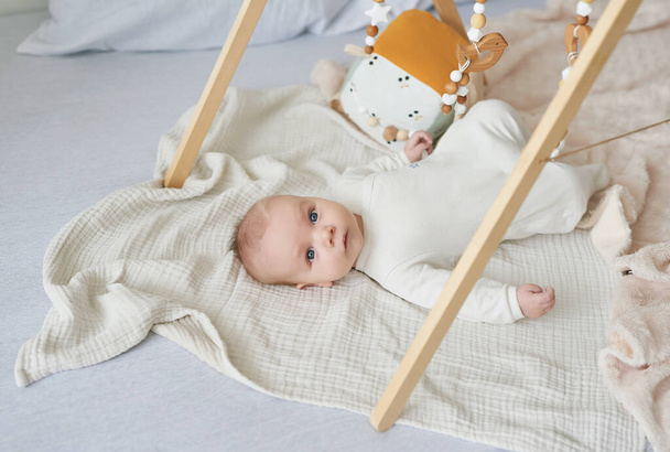 Newborn toddler boy lies and plays with educational toys. Happy motherhood and fatherhood. Maternity hospital and clinic. Father and mother day. Early childhood development. - 写真・画像