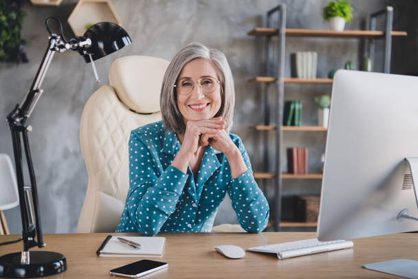 Photo of cheerful positive happy nice old woman wear glasses good mood office worker indoors inside workplace - Foto, Imagen