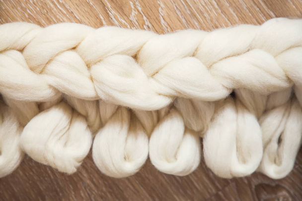 O processo de tricotar uma planície de grande tricô de lã de merino. Trabalho inacabado com laços abertos no chão de madeira - Foto, Imagem