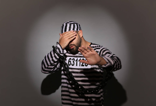 Prisoner in special uniform with chained hands on grey background - Foto, Imagem