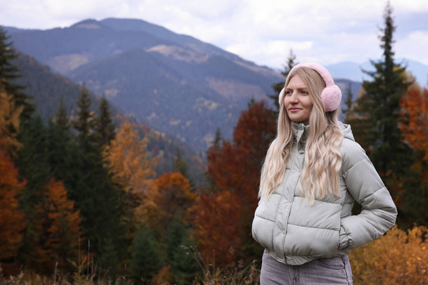 Young beautiful woman wearing warm earmuffs in mountains - Valokuva, kuva