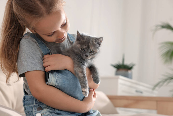 Cute little girl with kitten at home, space for text. Childhood pet - Fotografie, Obrázek