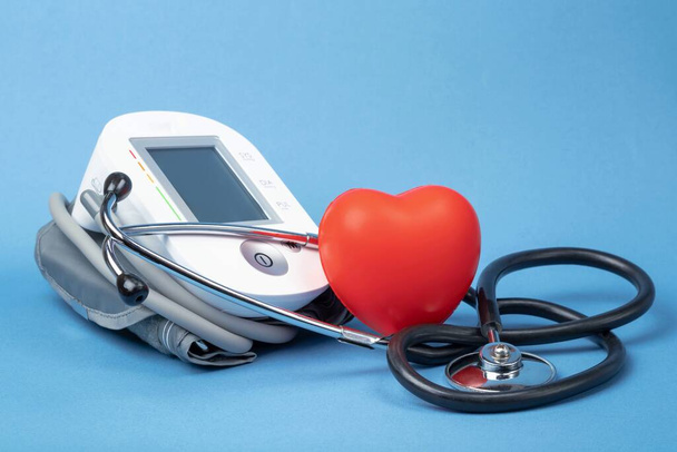 Stethoscope, blood pressure monitor and rubber heart on a blue background with space for text. Heart health, healthcare concept. - Photo, Image