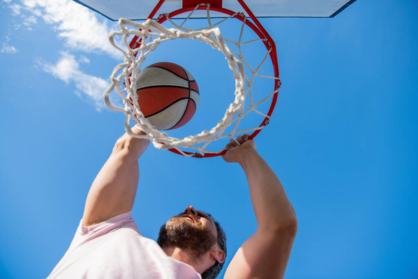 баскетболист бросает мяч в обруч на открытом воздухе, прицеливаясь - Фото, изображение