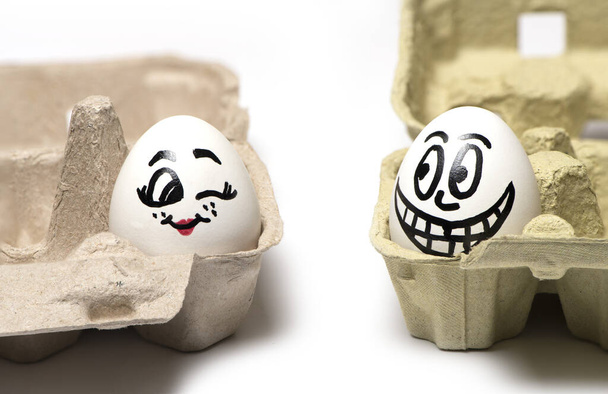 Nahaufnahme von zwei Eiern mit bemalten Gesichtern eine Frau mit einem Mann lustig flirtet isoliert auf weißem Hintergrund - Foto, Bild