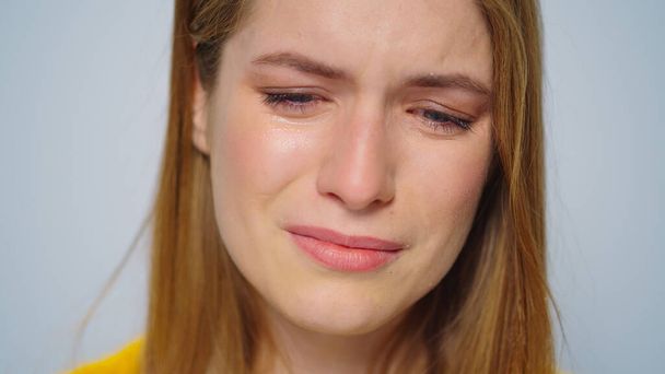 Closeup γυναίκα που κλαίει ποζάροντας με λυπητερή διάθεση σε γκρι φόντο στο στούντιο. - Φωτογραφία, εικόνα