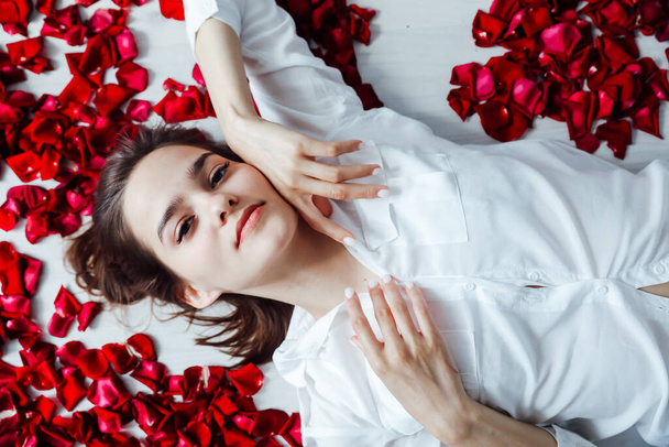 una hermosa mujer yace en los pétalos de las rosas rojas - Foto, imagen