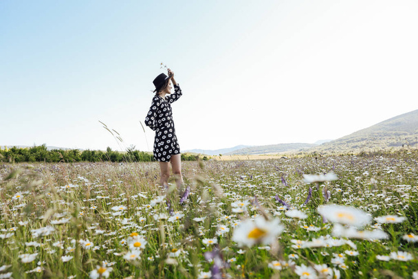 a beautiful woman walks through a field of daisies - Photo, Image