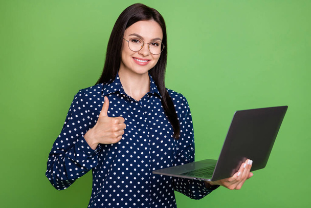 Foto van optimistische brunette hairdo hr dame houden laptop show duim up dragen bril blauw shirt geïsoleerd op groene kleur achtergrond - Foto, afbeelding