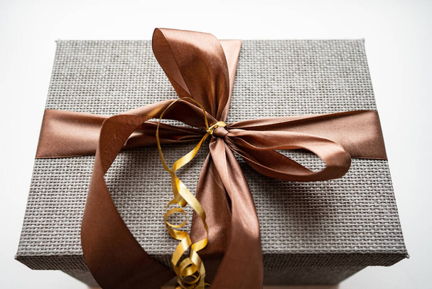 Grey gift box with brown ribbon on a white background.  - Zdjęcie, obraz