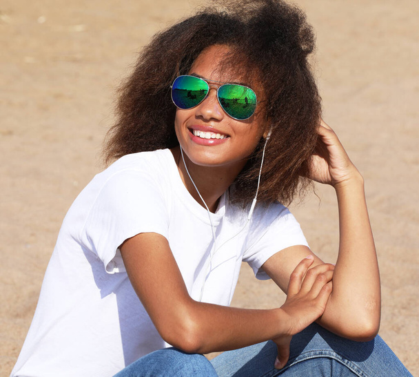 Amazing afro american young woman in sunglasses listening to music in headphones. - Foto, Bild