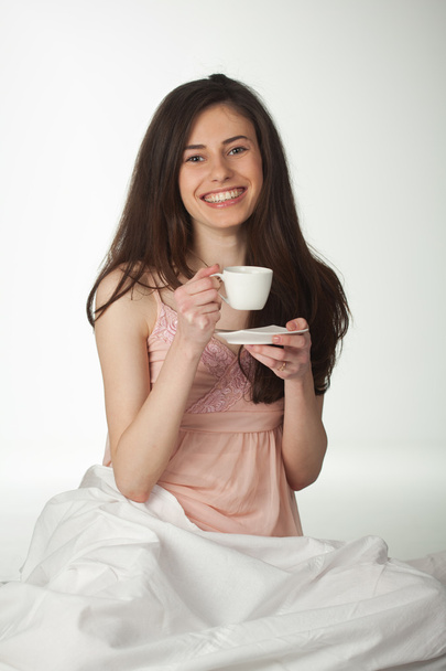 lächelndes Mädchen im Bett mit einer Tasse Kaffee - Foto, Bild