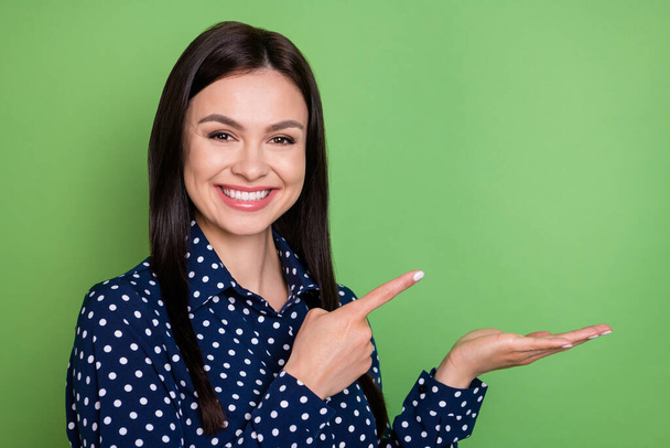 Photo of happy cheerful young woman point finger hold hand empty space object isolated on green color background - Foto, Imagem