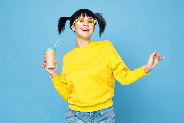 cheerful woman with pigtails in yellow sweater drink blue background - Foto, Bild