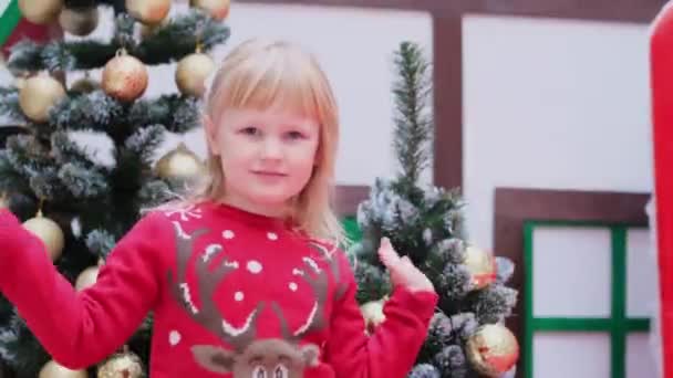 dziewczynka w swetrze świątecznym fale dłoni dłoń w cześć gest wita kogoś - Materiał filmowy, wideo