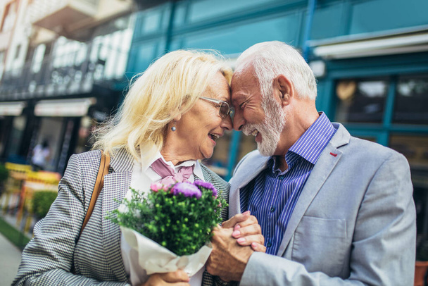 Ρομαντικός ηλικιωμένος που δίνει λουλούδια στη γυναίκα του  - Φωτογραφία, εικόνα
