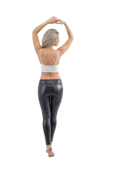 Beautiful girl in black fitting leggings. Women's legs in leather legits. Light background. - Photo, Image