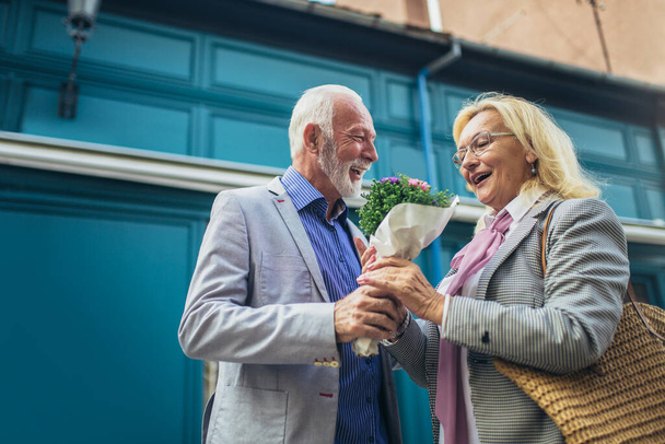 Romantische senior man geven zijn vrouw bloemen  - Foto, afbeelding