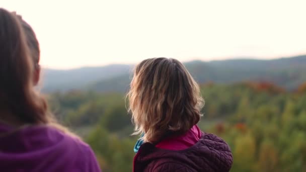 Kaksi tyttöä ihailee vuoristomaisemaa auringonlaskun aikaan. - Materiaali, video