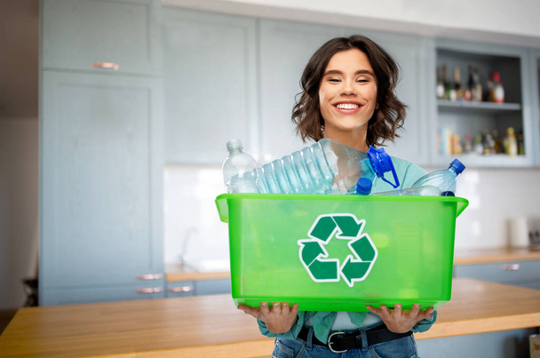 happy young woman sorting plastic waste on kitchen - Fotó, kép