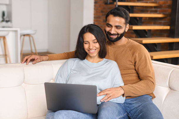 Serene Indian couple spending time together at home, using laptop - Foto, imagen