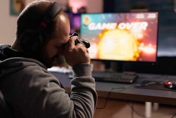 Λυπηρός άνθρωπος χάνει βιντεοπαιχνίδια μετά το παιχνίδι με joystick - Φωτογραφία, εικόνα