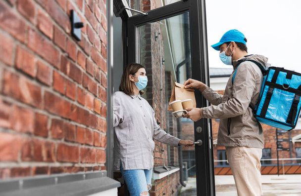 food delivery man in mask giving order to customer - 写真・画像