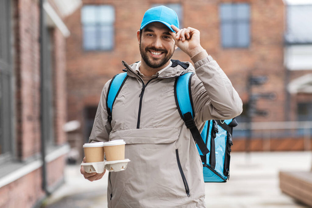 happy delivery man with thermal bag and coffee - 写真・画像