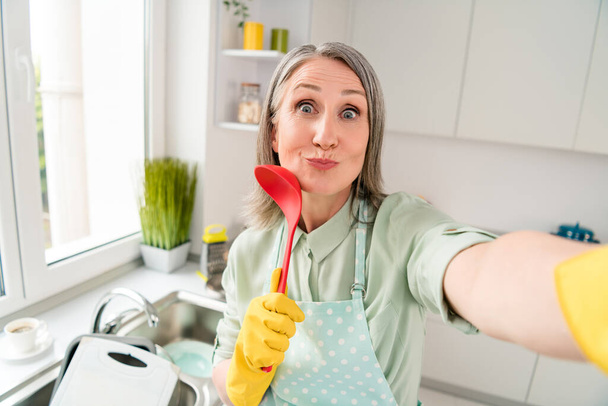 Self-portrait of attractive cheerful grey-haired woman doing dishes cleanup having fun good mood at home light white indoor - Foto, Imagem
