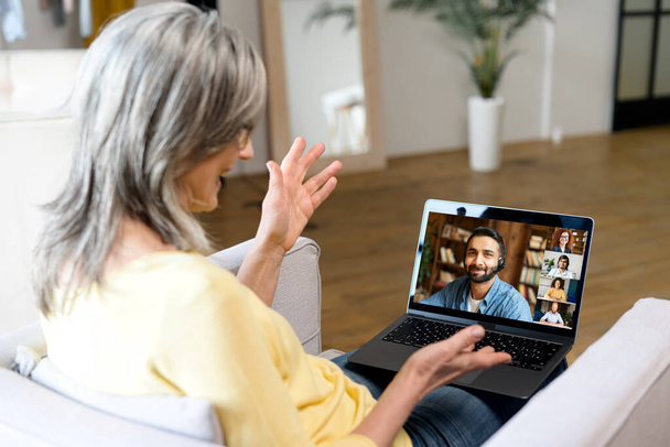 Mujer mayor de cabello gris que utiliza la plataforma en línea para la comunicación en línea con sus colegas - Foto, Imagen