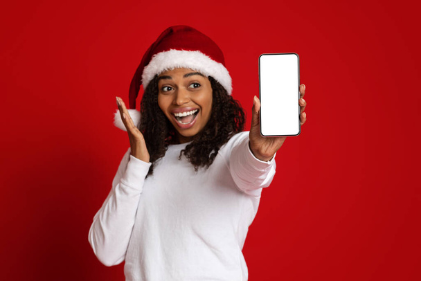 Thrilled black lady in Santa hat showing cellphone, mockup - Fotoğraf, Görsel