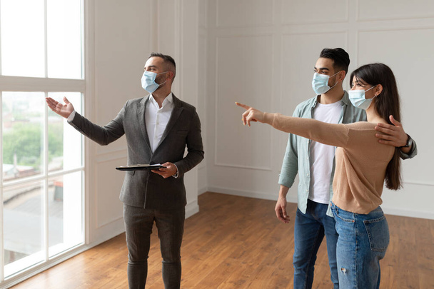 Férfi ingatlanügynök orvosi maszkban Vásárlók mutatása Új apartman - Fotó, kép