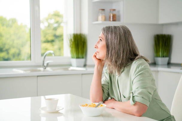 Profile side view portrait of attractive dreamy grey-haired woman dreaming eating useful lunch at home light white indoors - Photo, Image