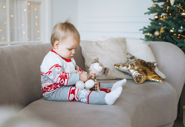 Cute little baby girl in winter overall in the room with Christmas tree at the home, happy New Year - Foto, Imagem
