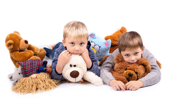 Funny little boys lying down with toys, isolated on white background - Photo, image