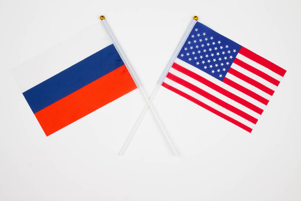Drapeau de la Russie et drapeau des États-Unis croisés les uns avec les autres sur le fond blanc. Russie vs USA. Rencontre entre les présidents de la Russie et des États-Unis. Isolé. Vue du dessus  - Photo, image