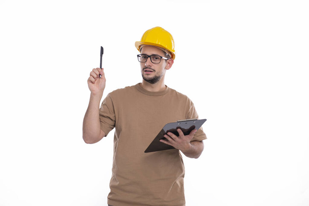 Erbauer hält Klemmbrett in den Händen und zeigt mit Stift nach oben. Bauarbeiter mit guter Idee. - Foto, Bild