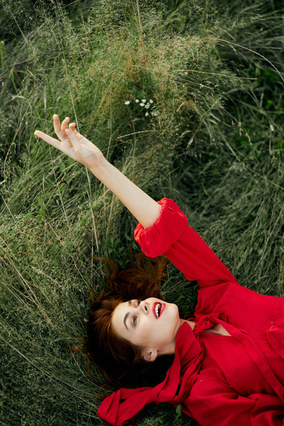 woman in red dress lies on the grass fresh air nature freedom - Foto, imagen