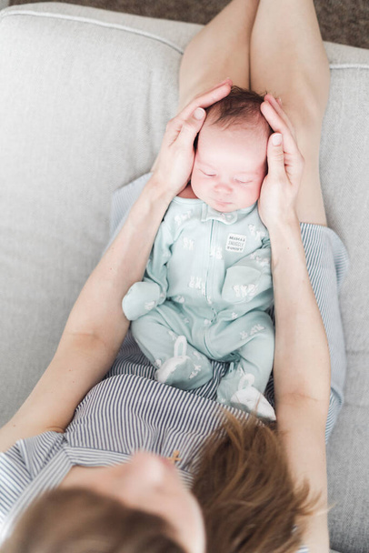 Lifestyle portret van een jonge moeder en haar pasgeboren, drie weken oude dochter. - Foto, afbeelding