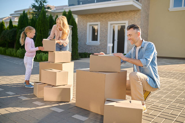 Family moving to a new house and carrying cardboard boxes - Foto, Imagen