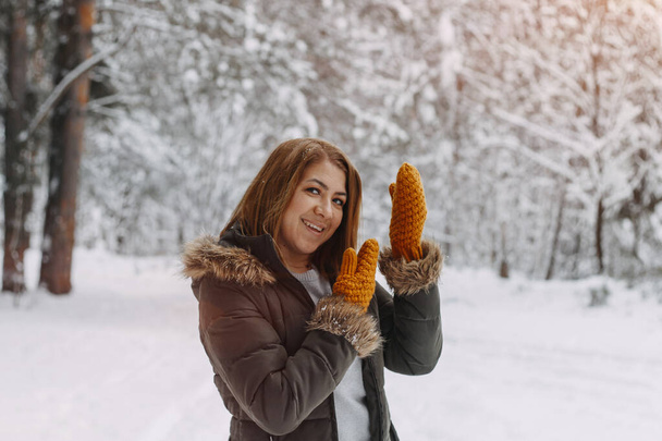 Portrait of a happy girl with a short haircut in mustard mittens in the forest after a snowfall . Christmas holidays, outdoor activities. - Valokuva, kuva