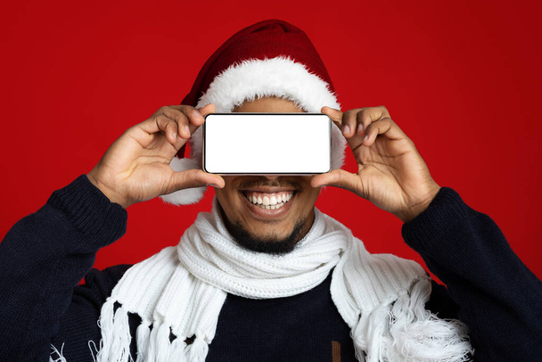 Alegre hombre afroamericano cubriendo los ojos con un teléfono inteligente - Foto, Imagen
