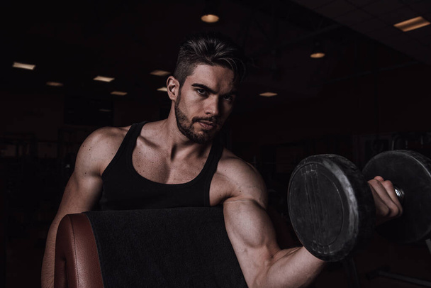  Hombre musculoso haciendo ejercicio en el gimnasio haciendo ejercicios con pesas en el bíceps Primer plano - Foto, imagen