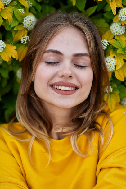 cheerful woman in a yellow sweater flowers nature fresh air - Fotografie, Obrázek