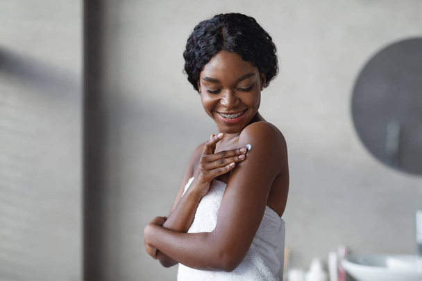Sensuale afro-americana giovane donna utilizzando addolcitore della pelle, interno del bagno - Foto, immagini
