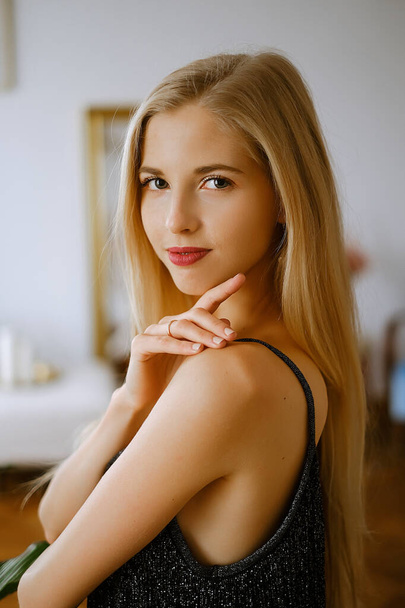 portrait of a young caucasian woman with blond hair and bright lips, a beautiful lady in an evening dress, a woman with nice clear skin and bright eyes looks at the camera - Фото, изображение