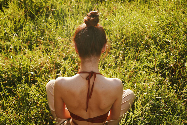 woman in the field sitting on the grass meditation rest - Foto, afbeelding