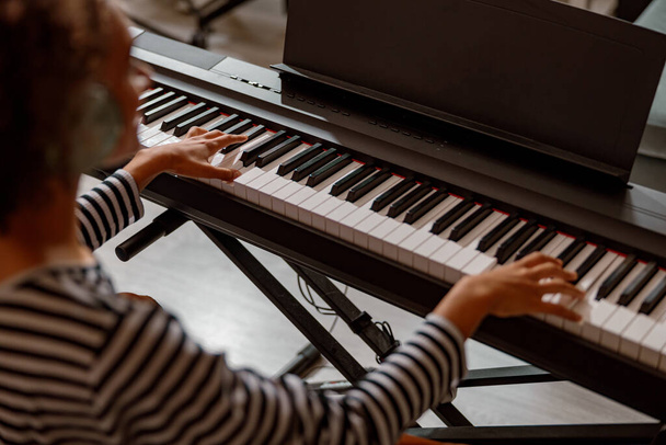 Multiraciale jonge vrouw spelen synthesizer thuis - Foto, afbeelding